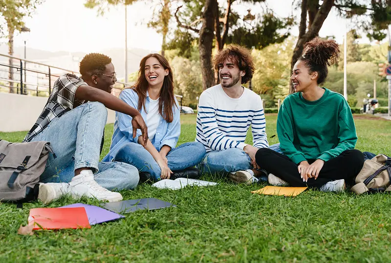 Group of friends sitting on grass smiling.