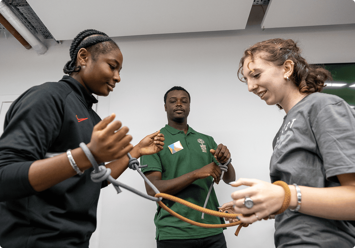 Three people practicing rope techniques indoors.